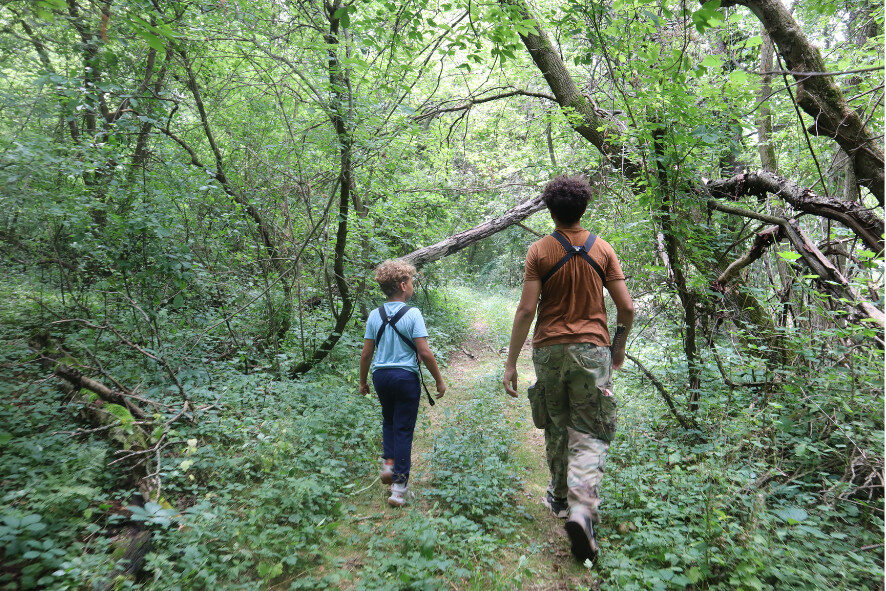 two young people walking through the forest on Christopher's property