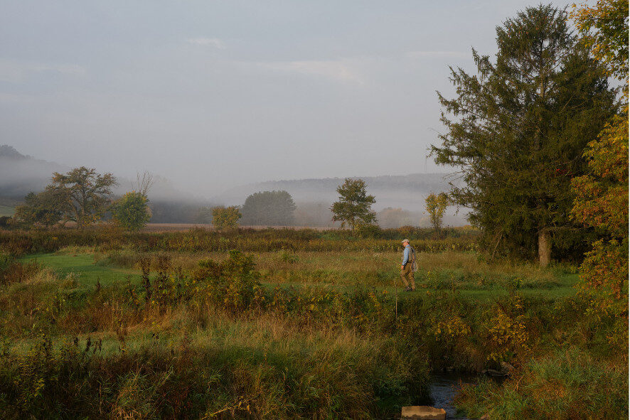 a person fly fishing in a creek on a foggy morning