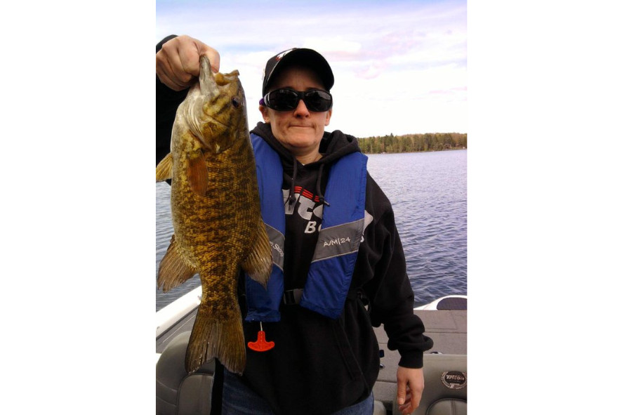 Person holding up a fish they caught while standing on a boat