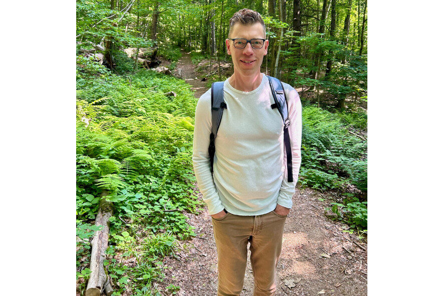 person wearing a backpack standing on a hiking trail 