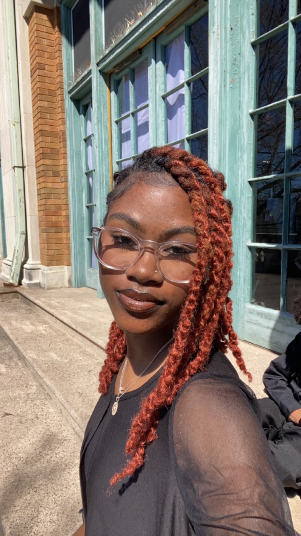 2024 Diversity in Conservation Internship cohort member smiling in front of a building with light blue window trimming