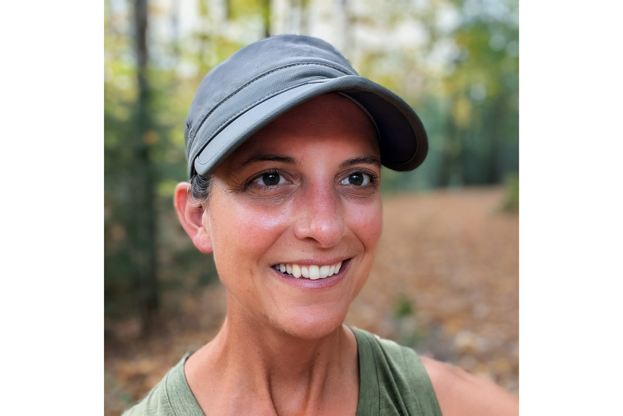 person wearing a hat smiling while in the woods