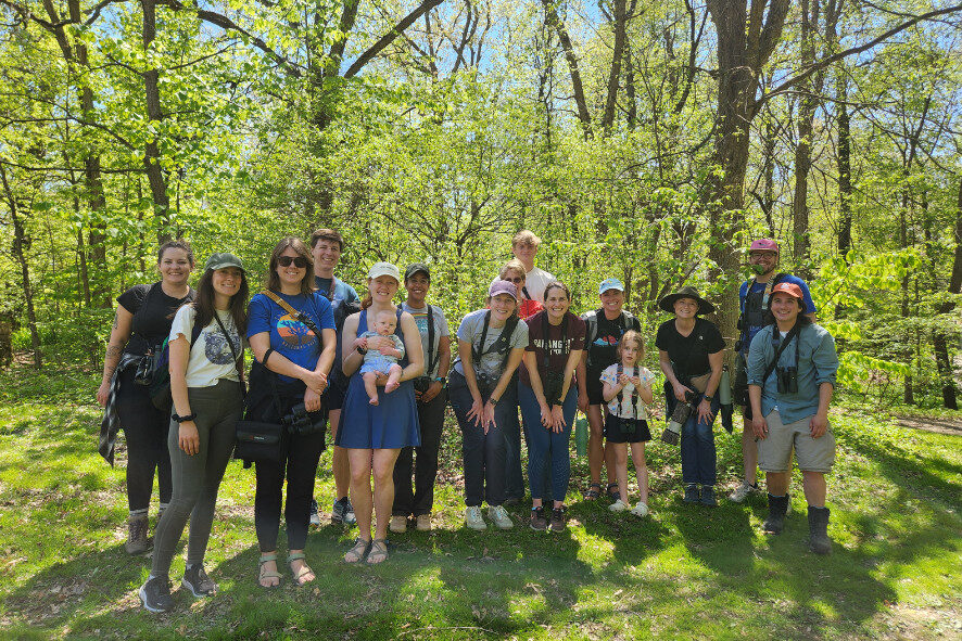 people taking a group photo in a forest