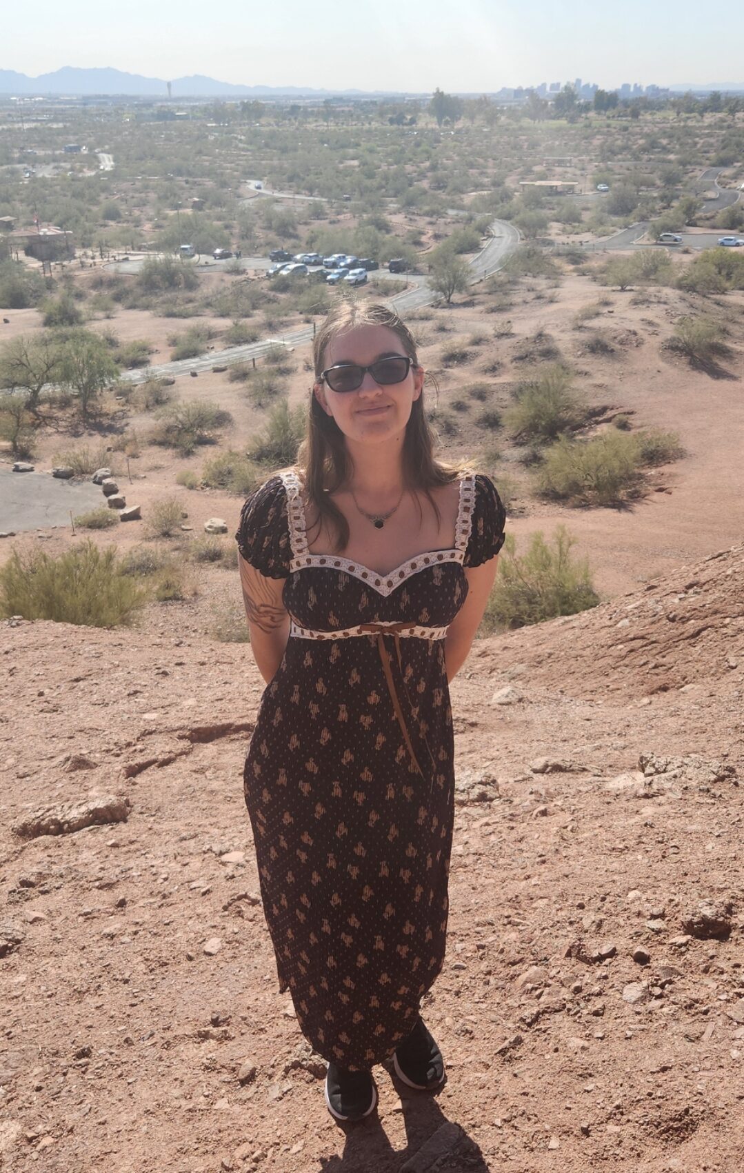 person in a dress standing on the top of a hill in the desert