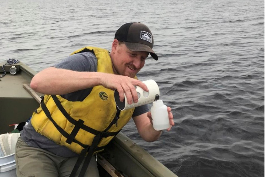 Person on a boat pouring something into a plastic jug