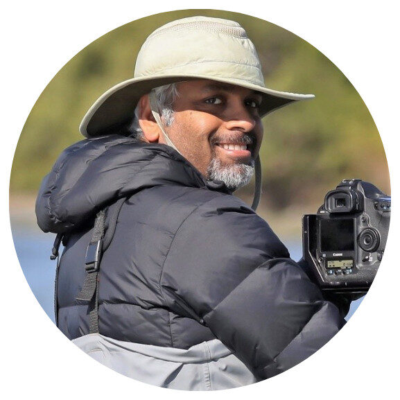 Sunil Gopalan standing next to his camera that is on a tripod