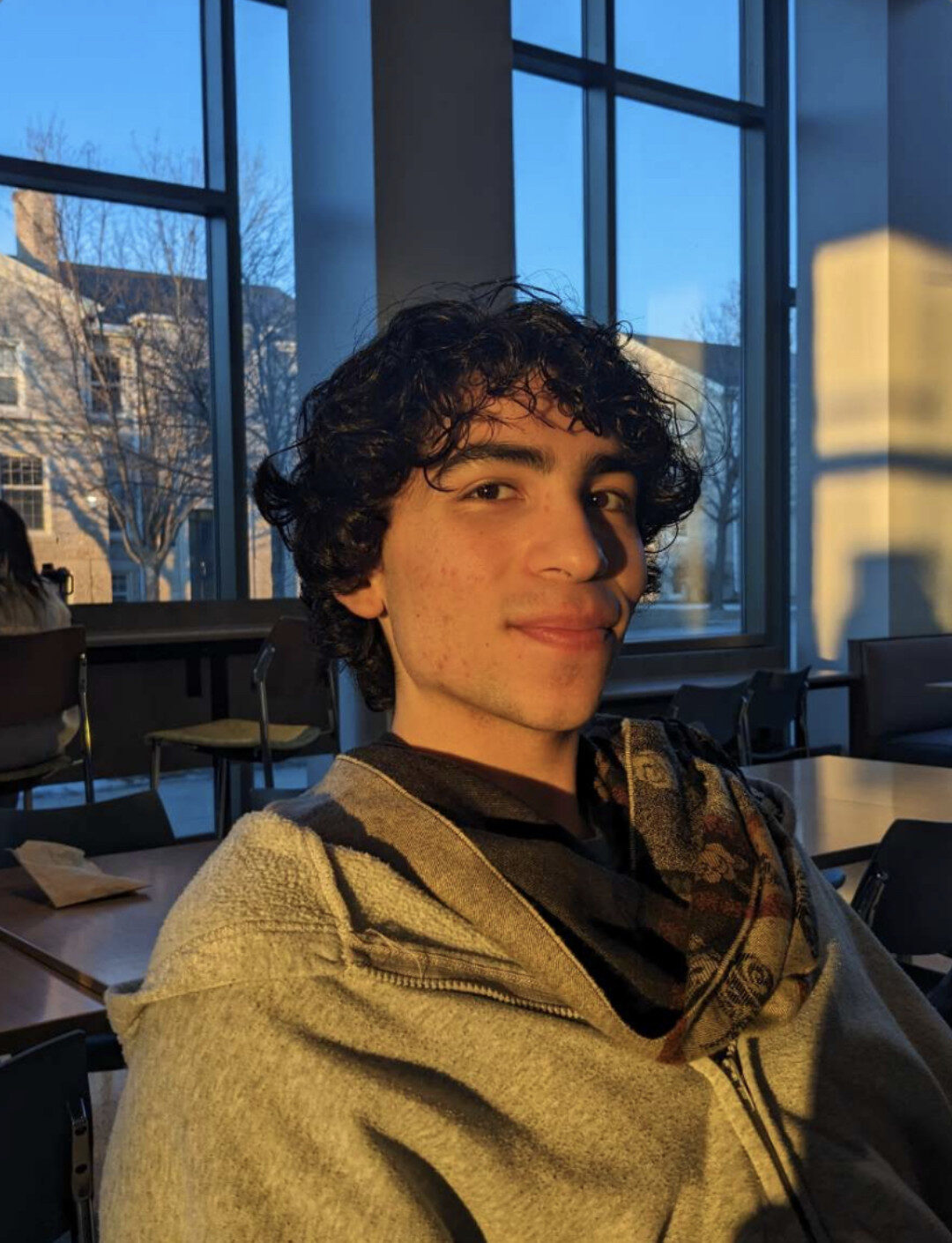 person smiling in front of a window as sunlight shines through